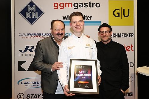 Gewinner des  NEXT CHEF AWARDS 2025 Gedion Beckmann (mitte) mit den Moderatoren Johann Lafer (li.) und Sebastian E. Merget (re.)